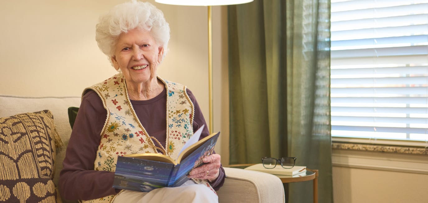 Senior resident reading a book in a cozy lounge area