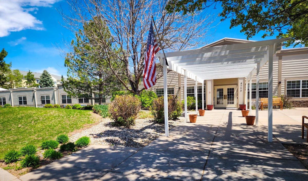 Entrance to The Residence at Oakridge with landscaping and American flag