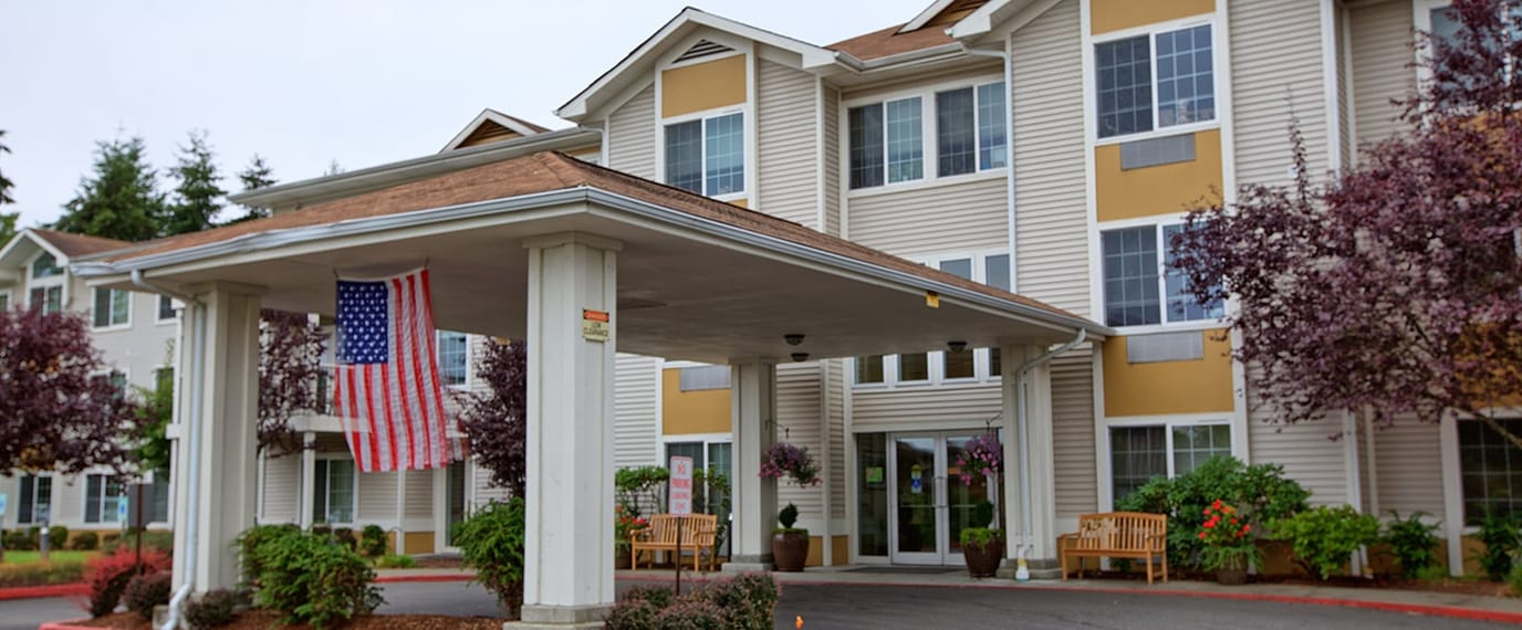 Entrance of Brookdale Allenmore with flag and landscaping