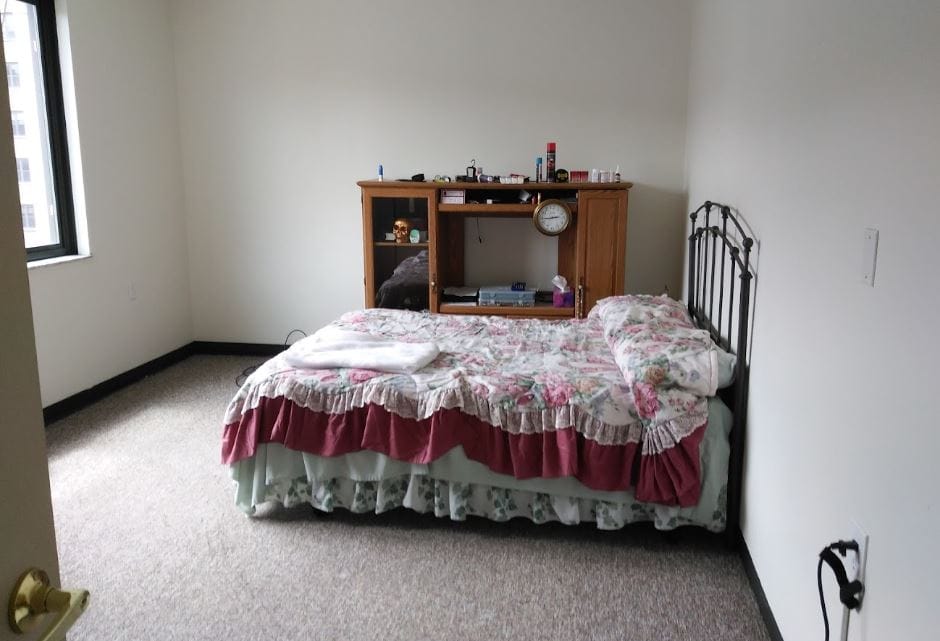 Brooks Manor, independent living in Charleston, WV — Unfurnished bedroom with floral bedding and wooden furniture
