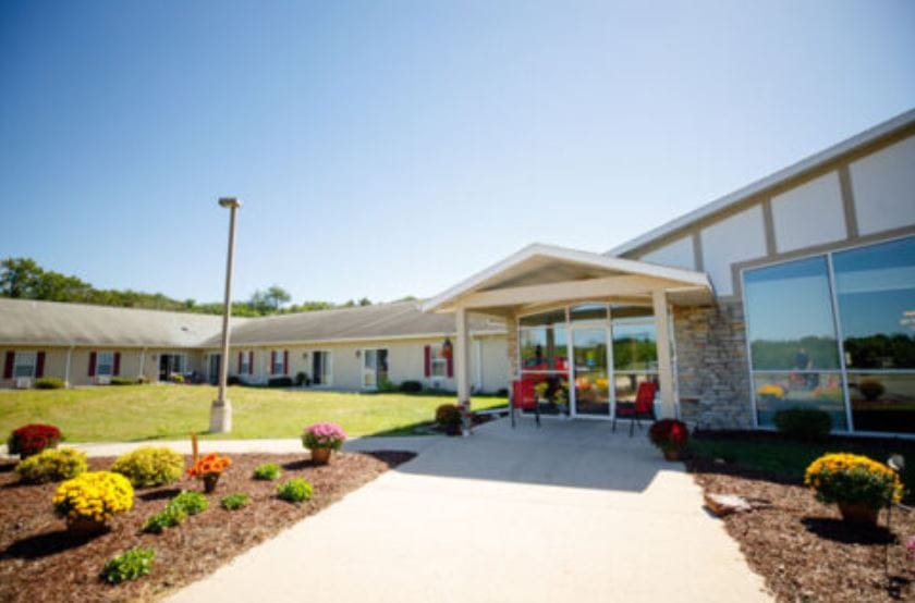 Exterior view of the Heritage of Portage entrance with flowers and seating area.
