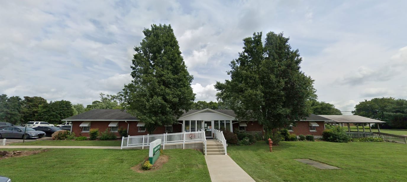 Exterior view of a senior living facility with trees and parking