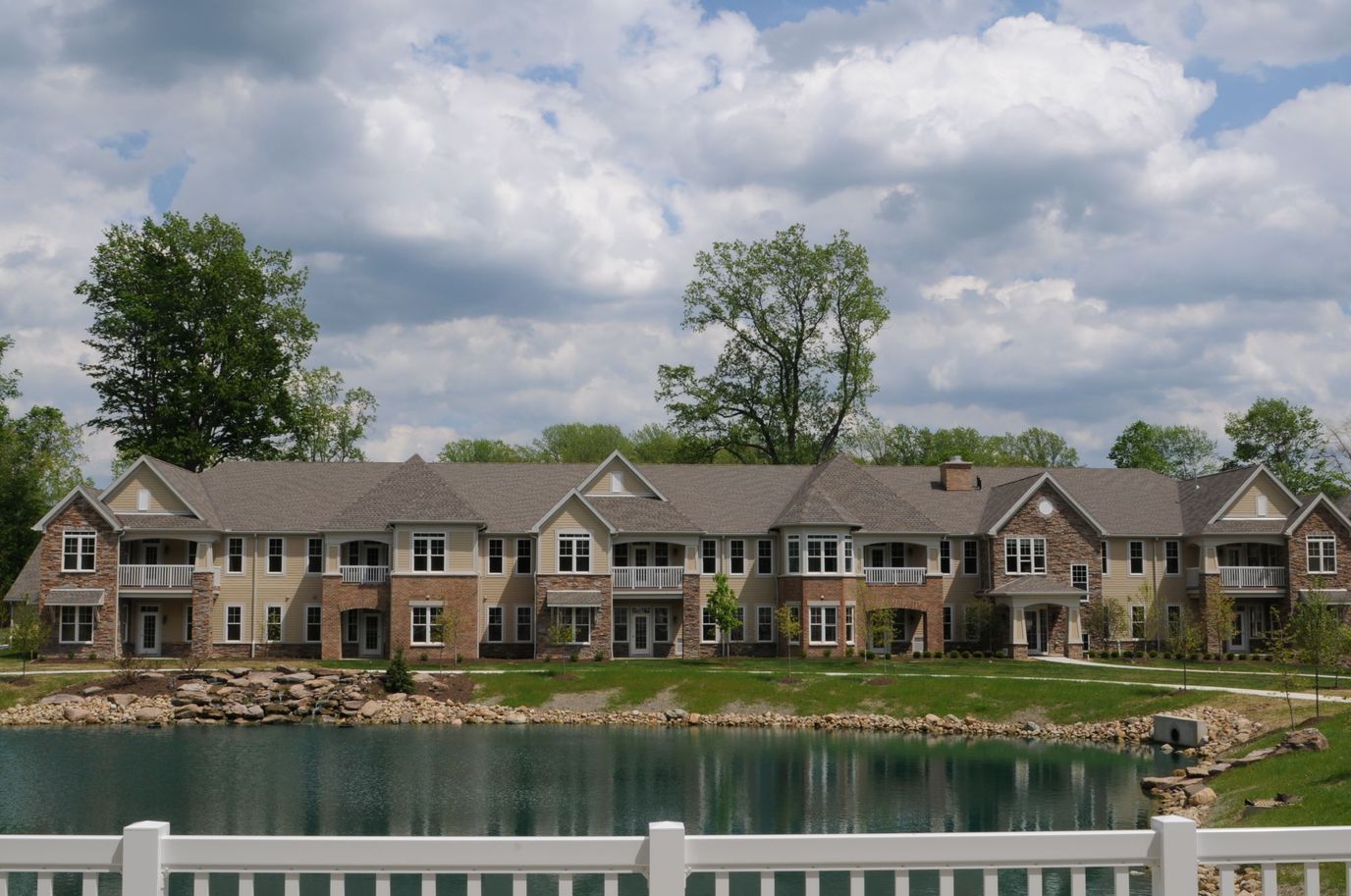 Exterior view of a senior living facility by a pond