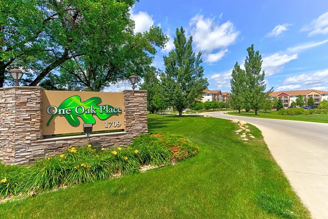 Entrance sign for One Oak Place with landscaped surroundings