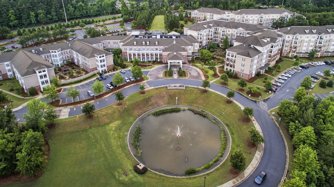 Aerial view of the facility with a pond and landscaping