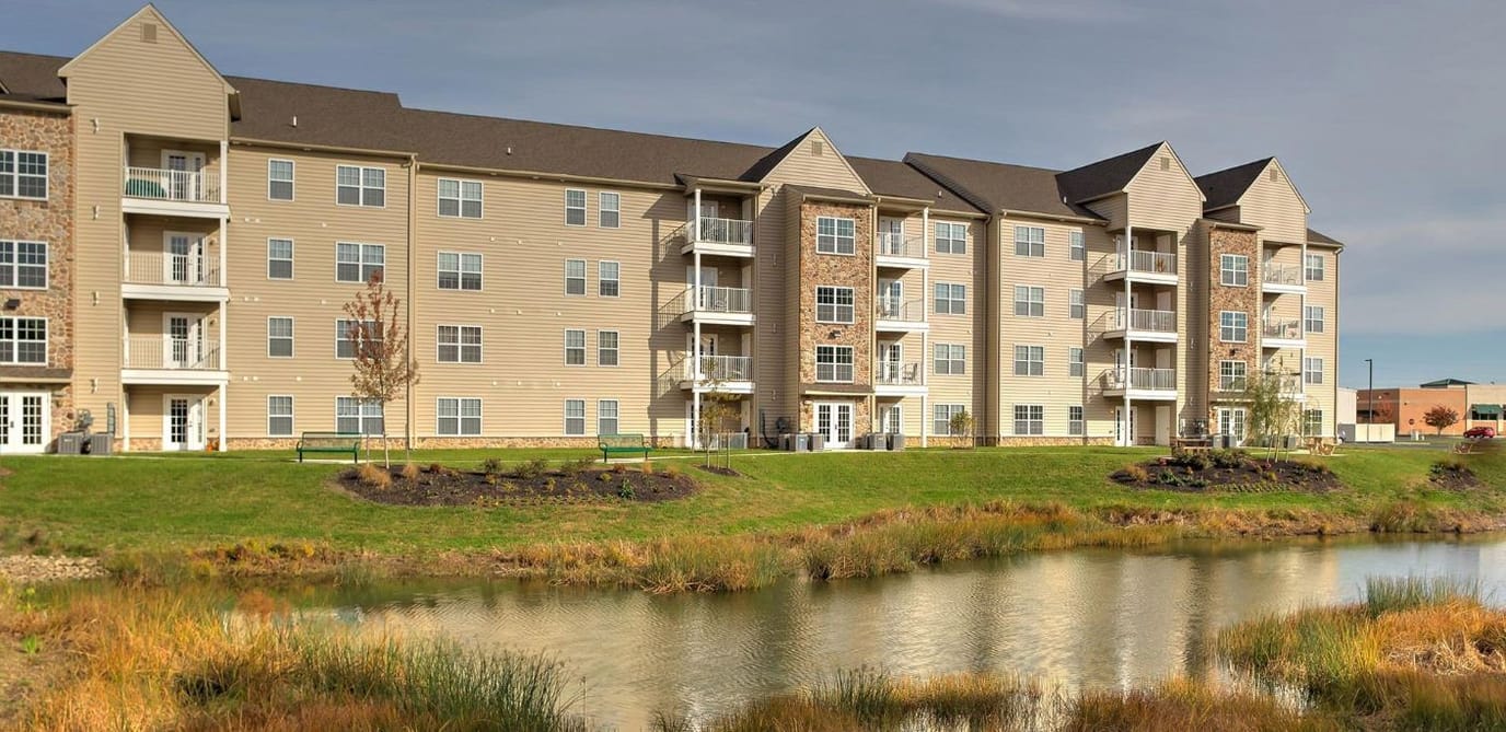 Exterior view of a senior living facility by a pond