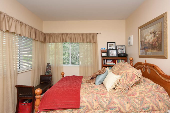 Comfortable bedroom with a bed, bookshelf, and window.