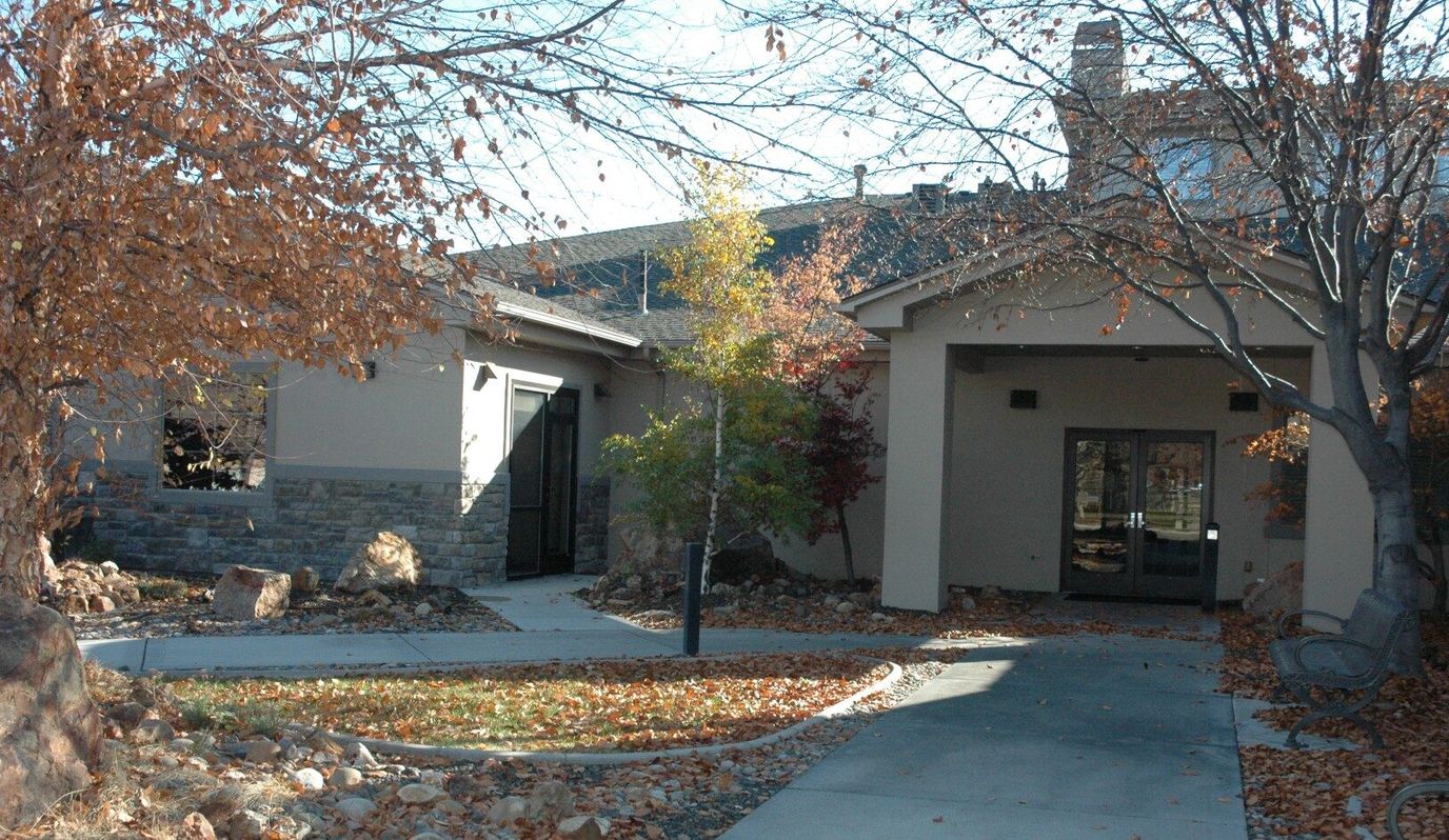 Exterior view of a nursing home facility entrance with autumn leaves