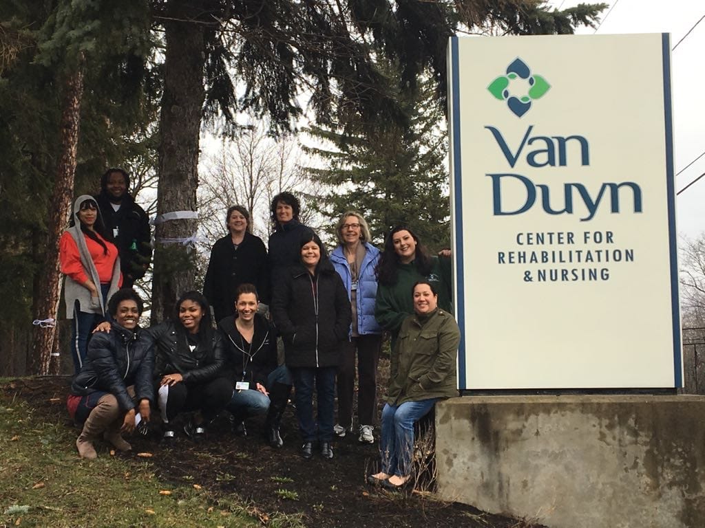 Staff members posing outside the Van Duyn Center sign