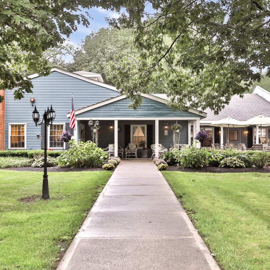 Front entrance of a senior living facility with a pathway and greenery