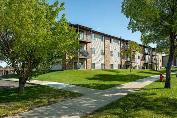 Cooperative Living Center, assisted living in West Fargo, ND — Multistory apartment building with green landscaping and pathway