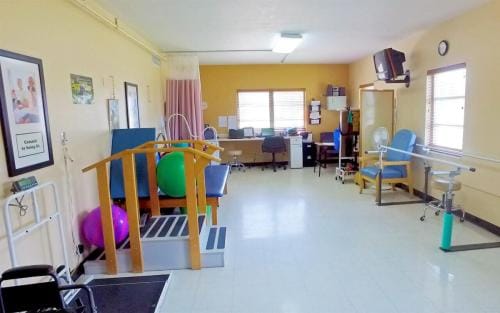 South Heritage Health & Rehabilitation Center, Nursing Home in St. Petersburg, FL — Rehabilitation therapy room with exercise equipment and office