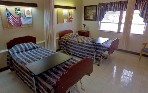 South Heritage Health & Rehabilitation Center, Nursing Home in St. Petersburg, FL — Shared bedroom with two hospital beds and decorations