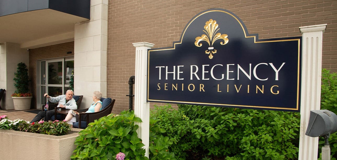 Residents enjoying time outside near the facility sign.