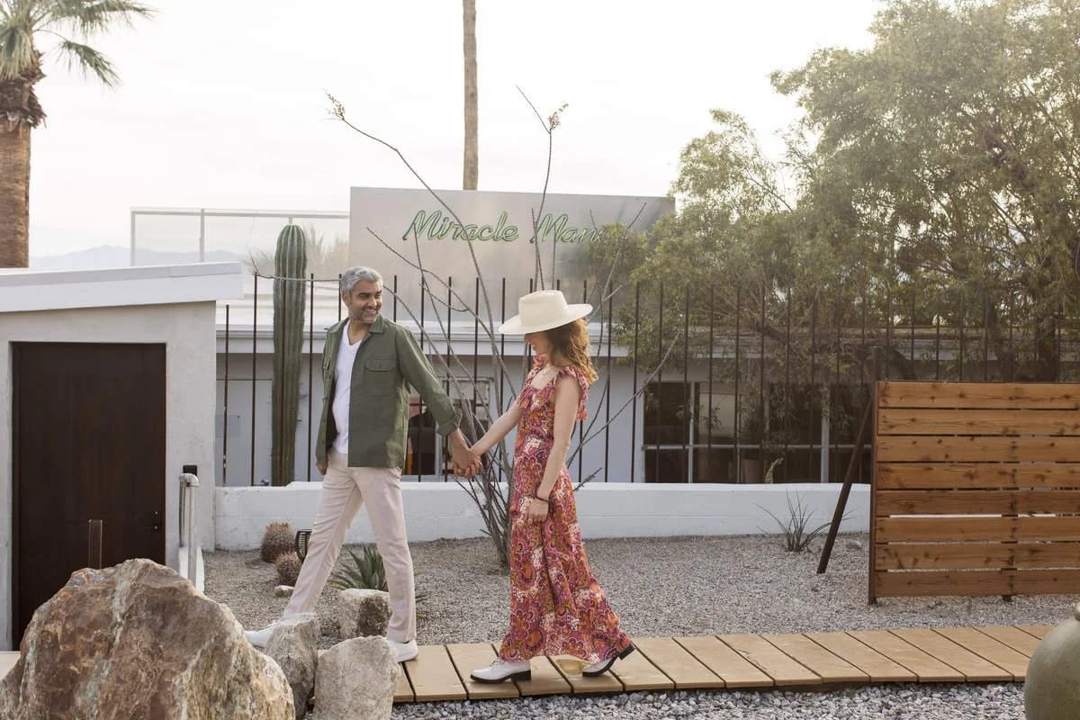Couple walking on a wooden path near Miracle Manor signage.