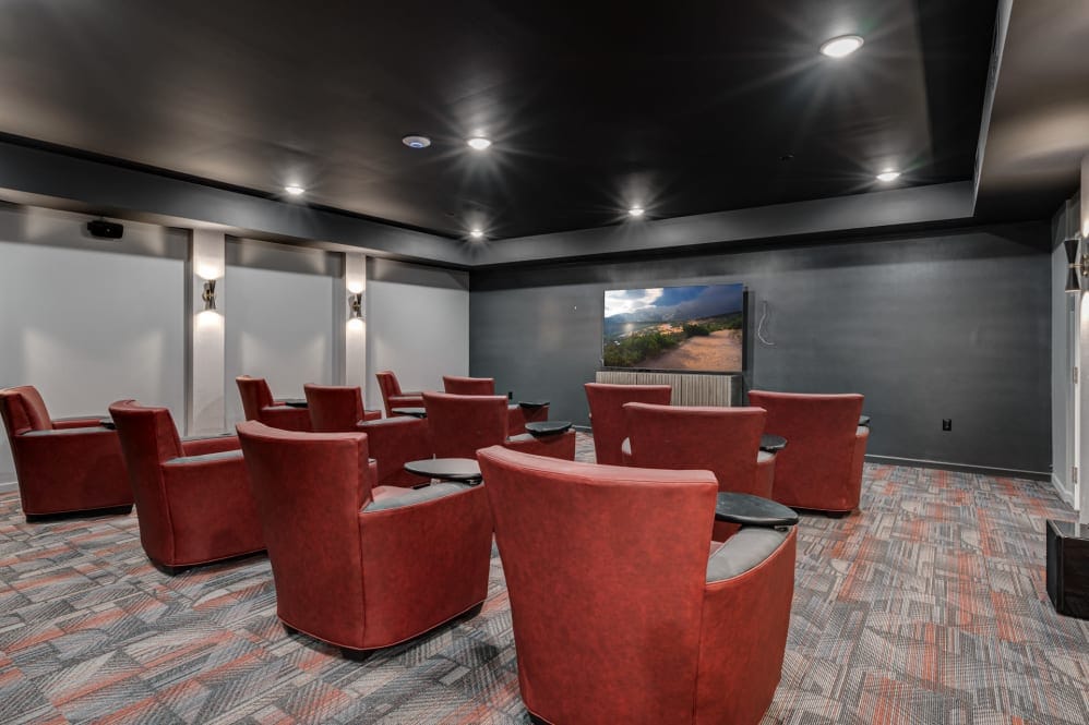 Cozy movie theater room with red chairs and a large screen