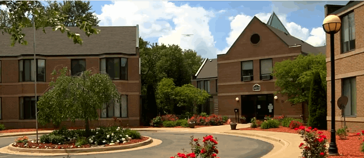 Exterior view of Holt Heritage Village with blooming flowers and greenery