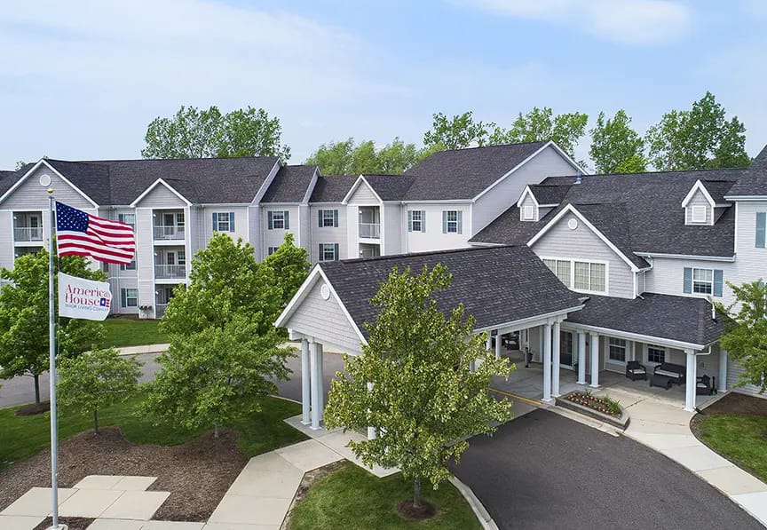 Aerial view of a senior living facility with trees and flag