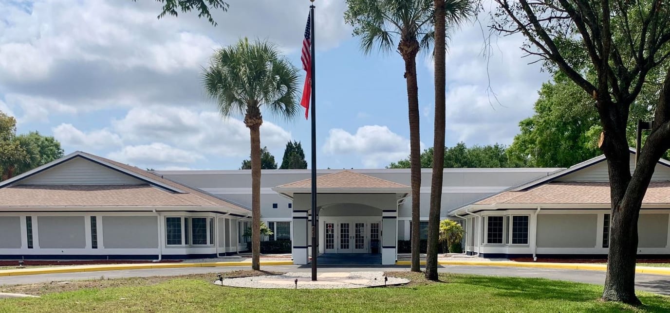 Exterior view of a senior living facility with palm trees
