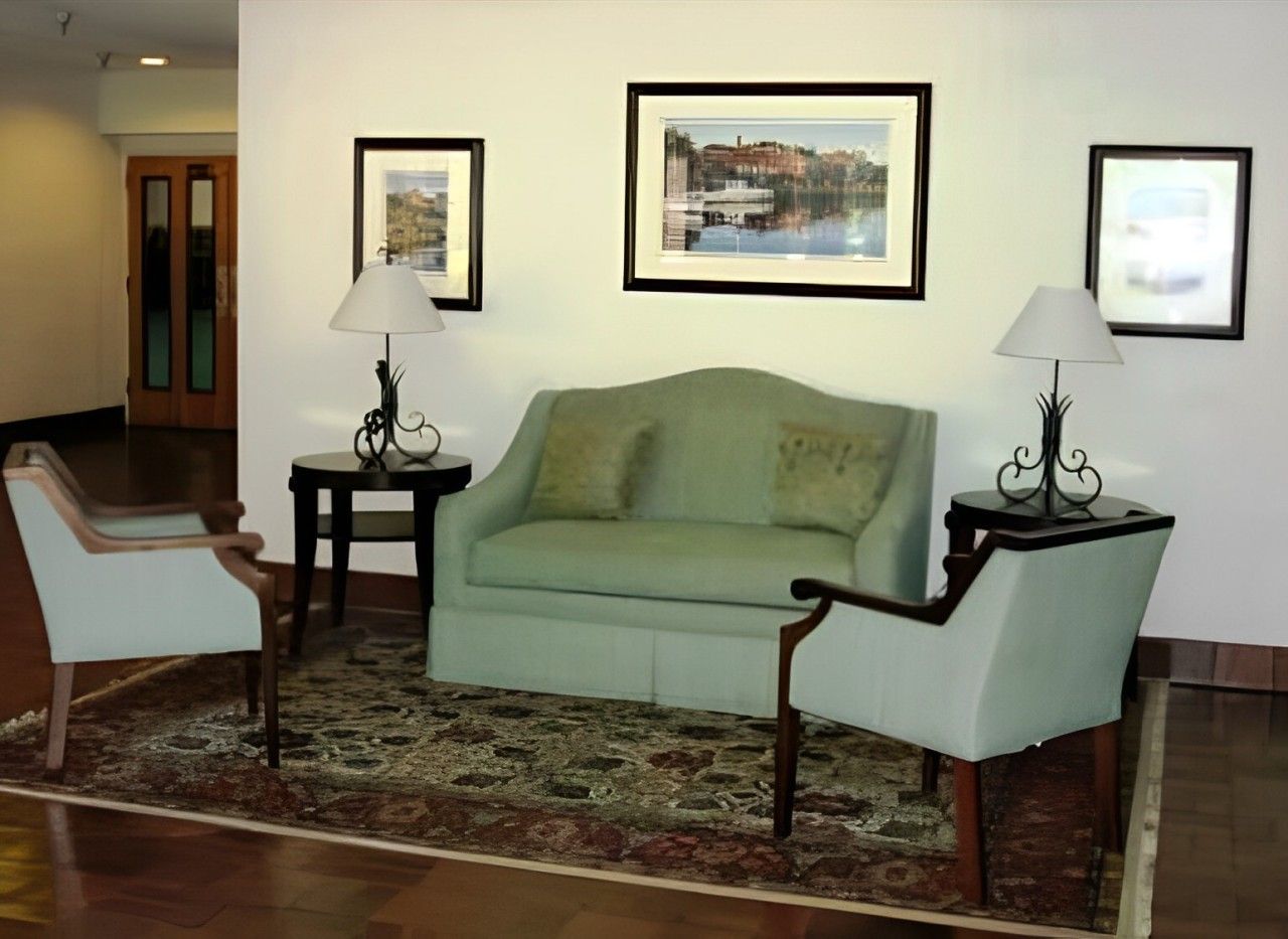Cozy living room setup with a green sofa and two chairs, decorative lamp, and framed artwork.