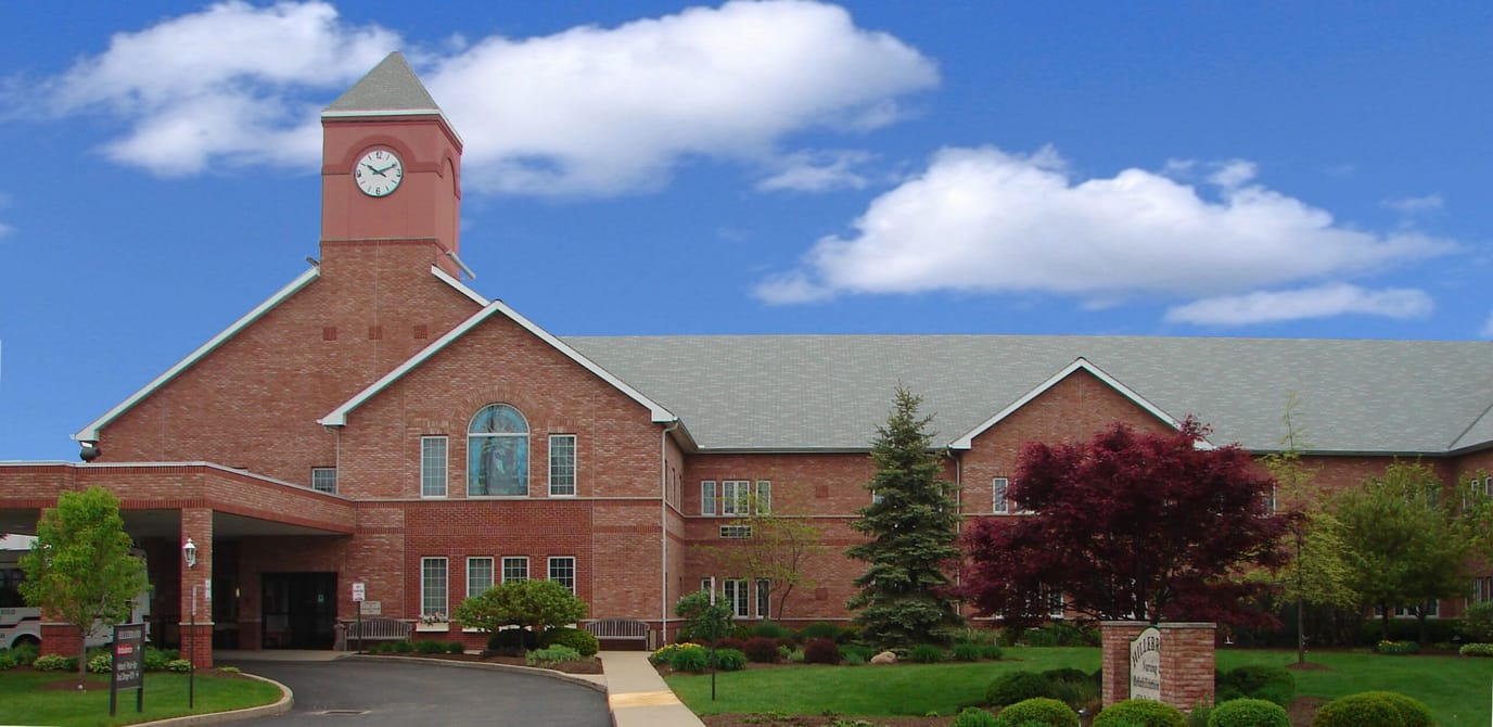Facility exterior featuring a clock tower and landscaped grounds