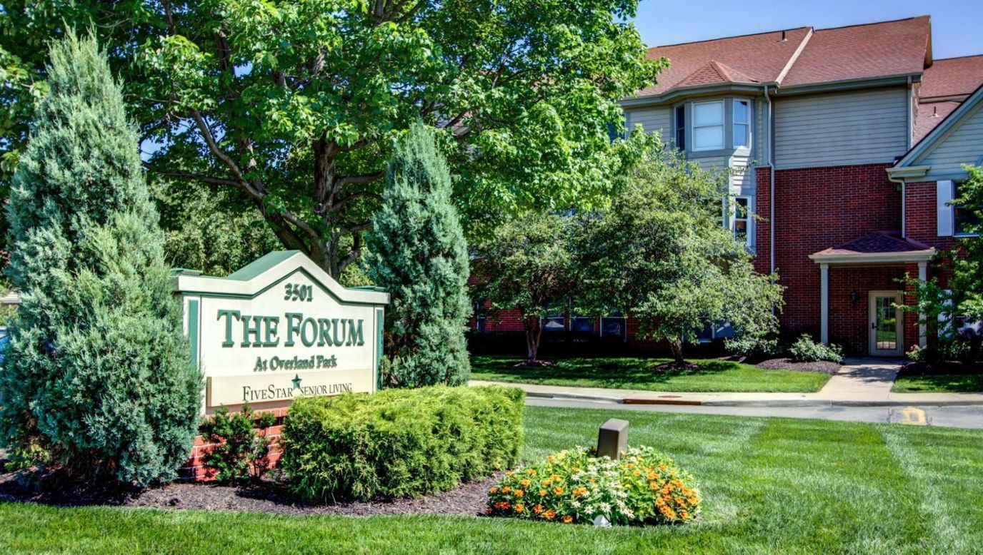 Exterior view of a senior living facility sign and landscaping