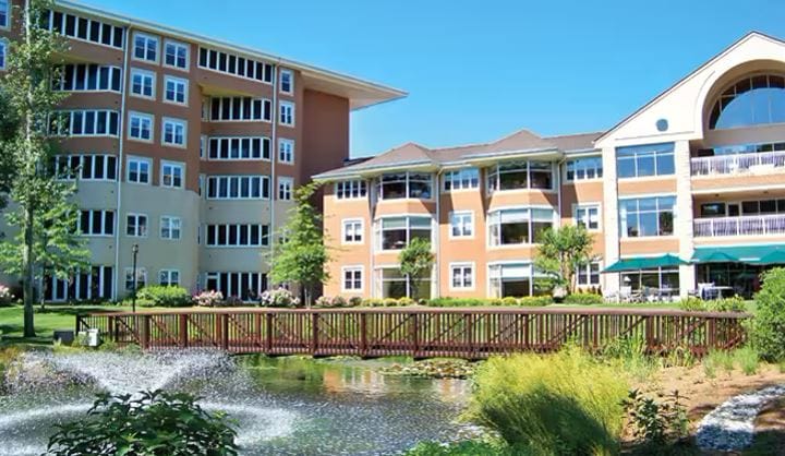 Exterior view of the facility with a pond and landscaping
