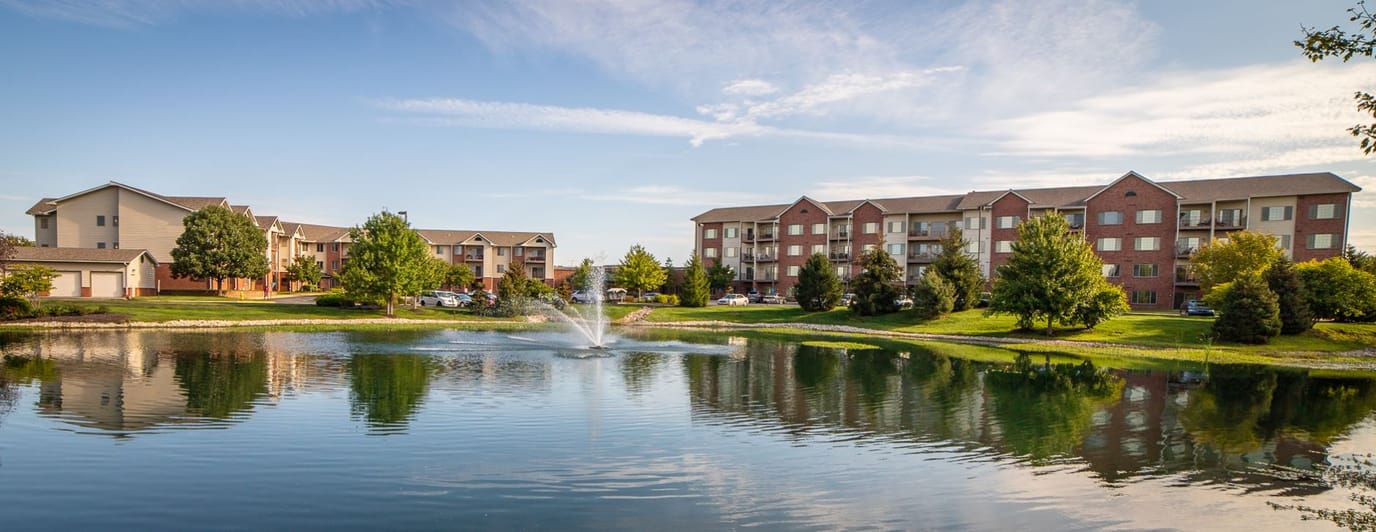 Exterior view of a senior living complex with a pond