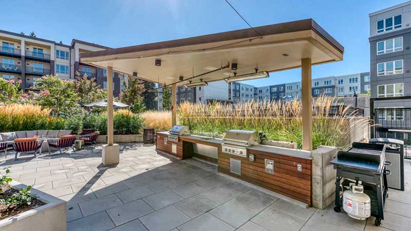 Outdoor grilling area with seating and landscaped surroundings