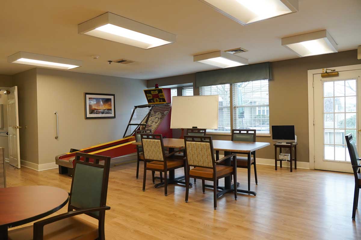A bright common area with tables and a game machine
