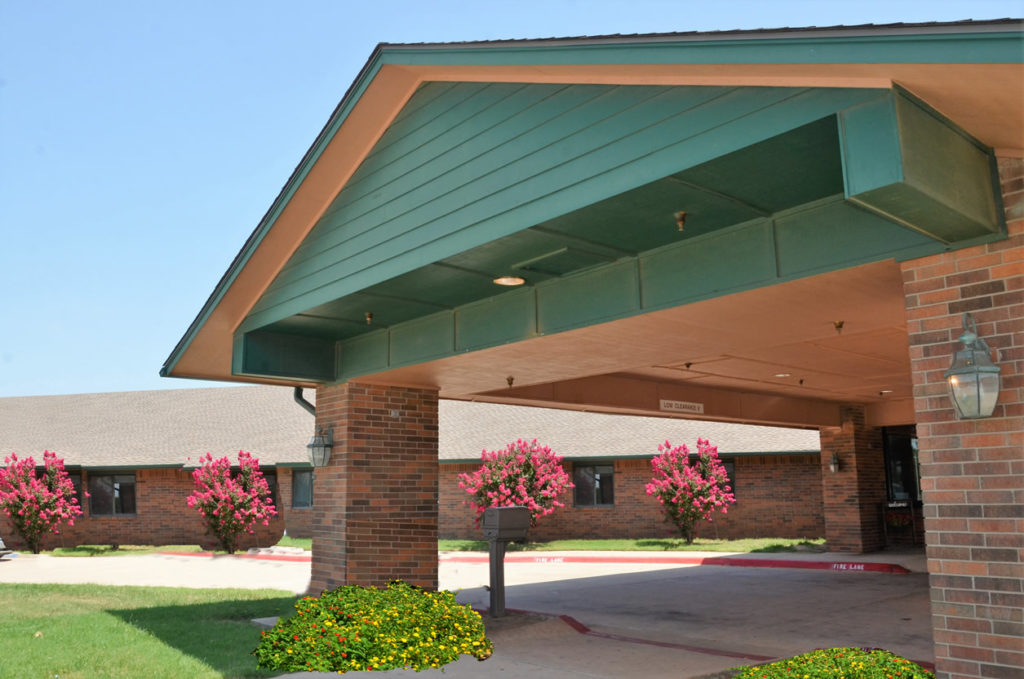 Entrance of a senior living facility with flower beds
