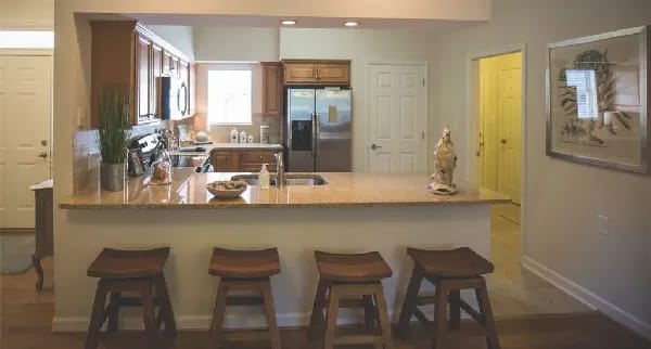 Bright kitchen area with stools around a bar