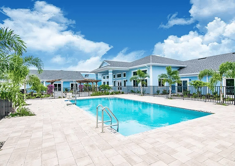 Outdoor swimming pool surrounded by palm trees and a blue sky