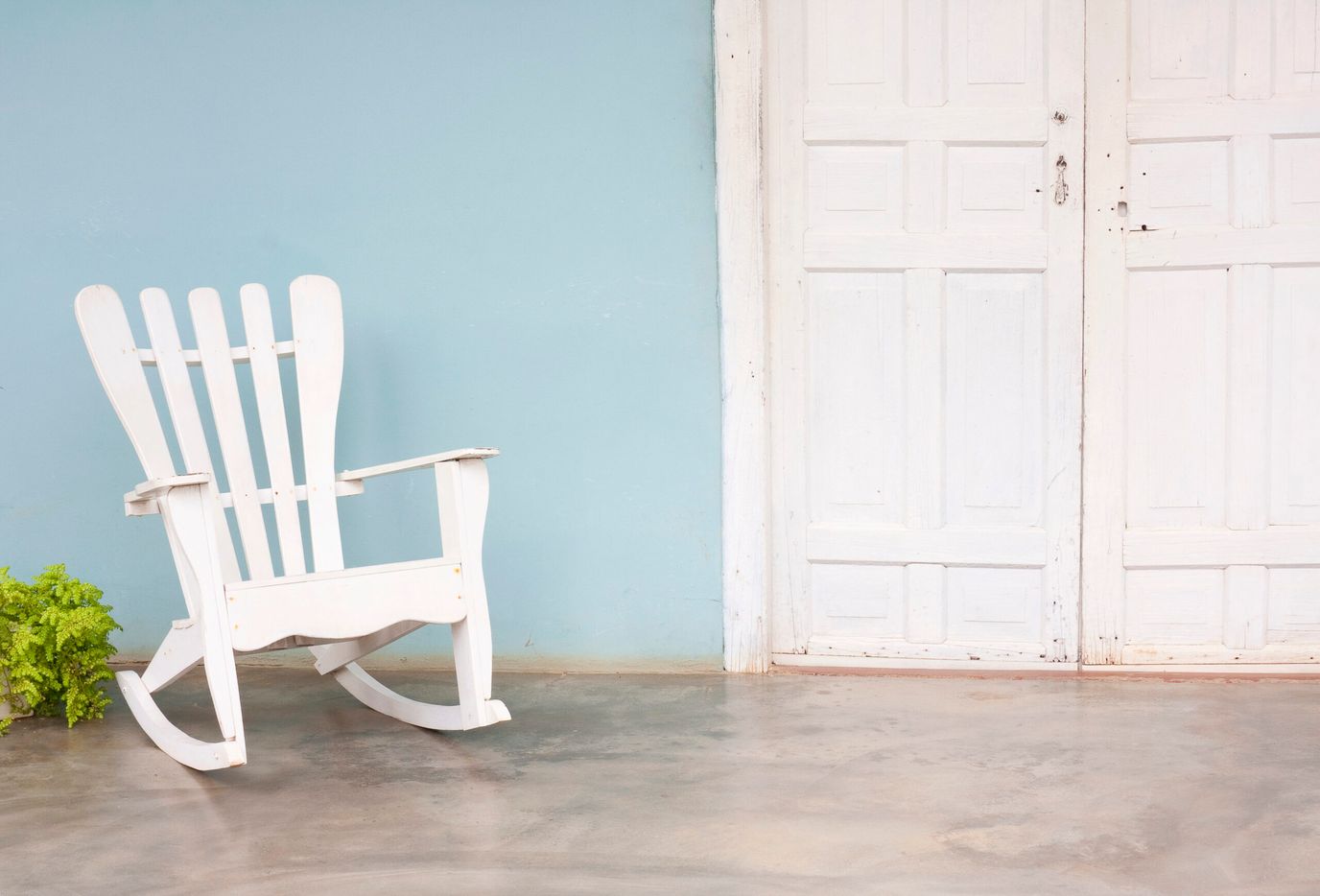 A white rocking chair against a blue wall