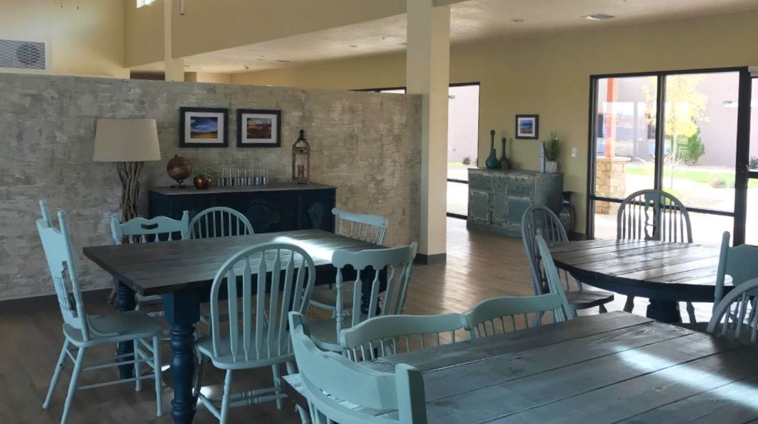 Bright and spacious dining area with wooden tables and blue chairs.