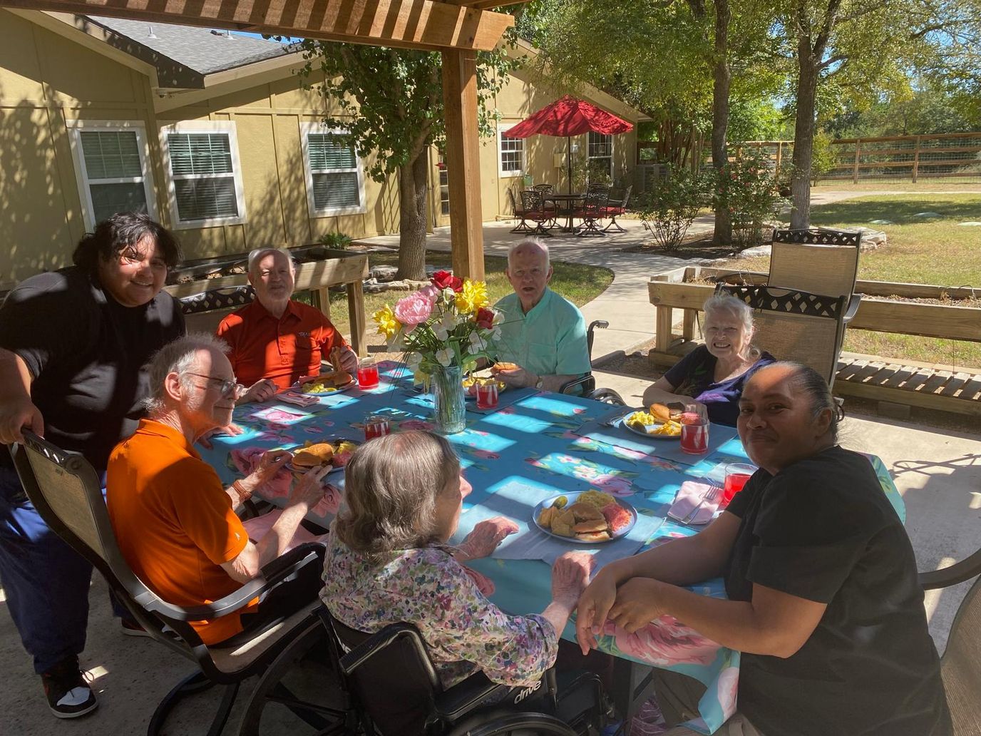 Residents and staff gather for an outdoor activity with food.