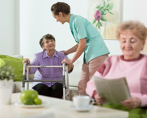 Care staff assisting residents in a communal living space