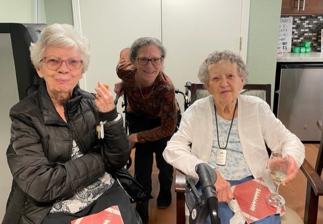 Two residents sitting together with staff member behind