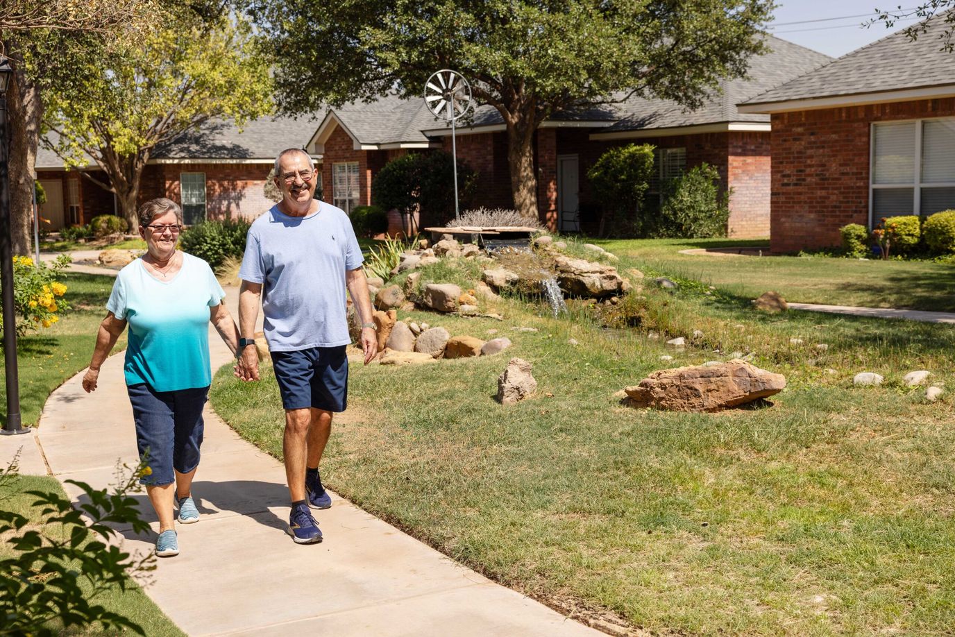 Two residents walking in a landscaped outdoor area.