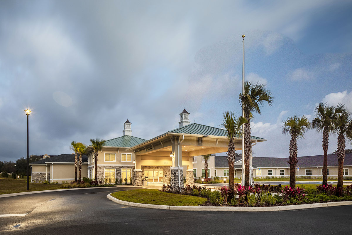 Entrance view of a senior living facility with palm trees