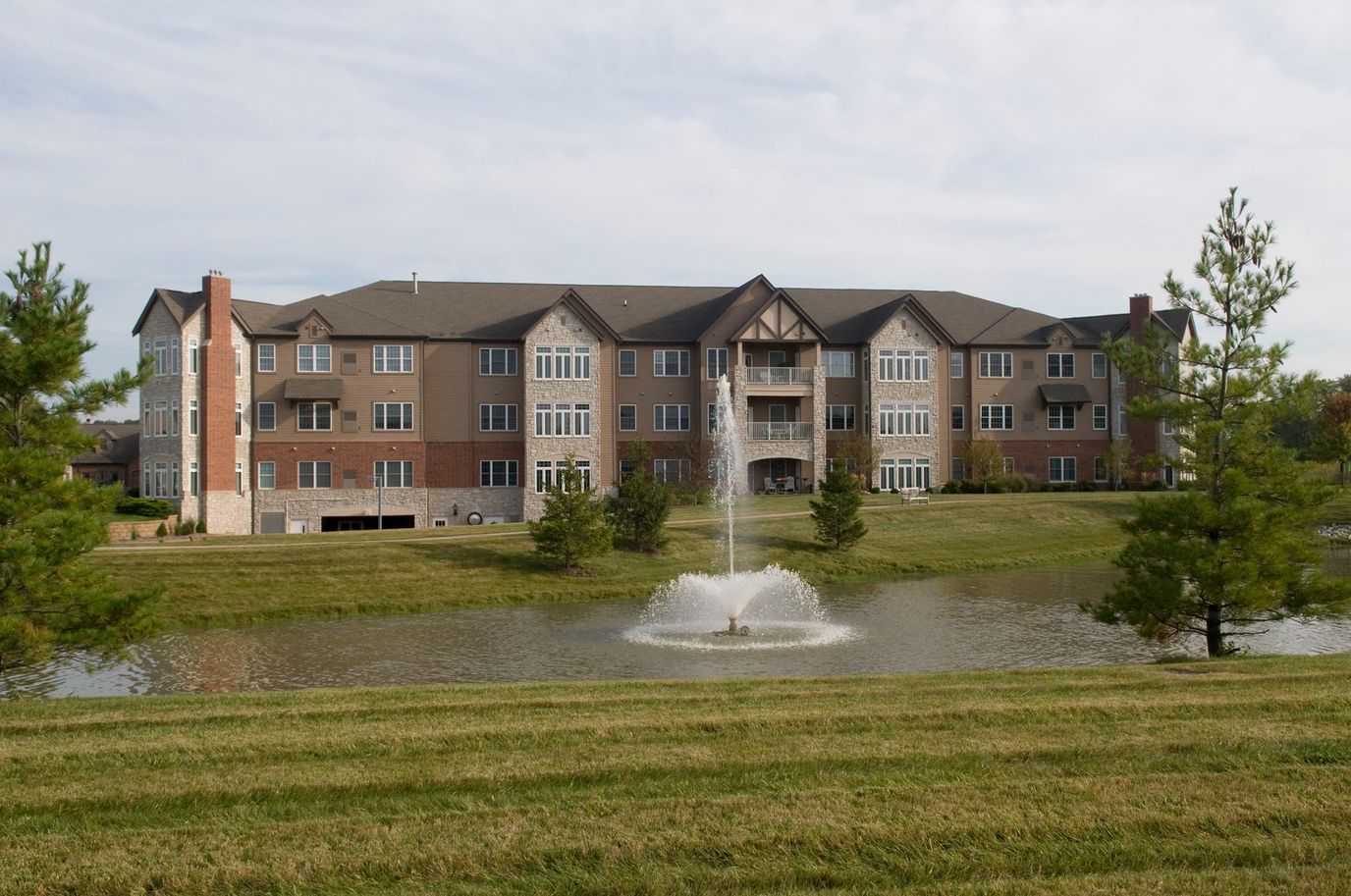 Exterior view of a senior living facility by a pond