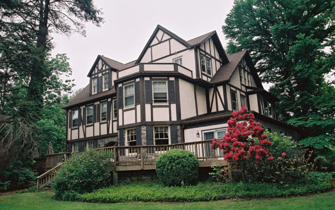 Tudor-style building set in lush greenery with vibrant flowers