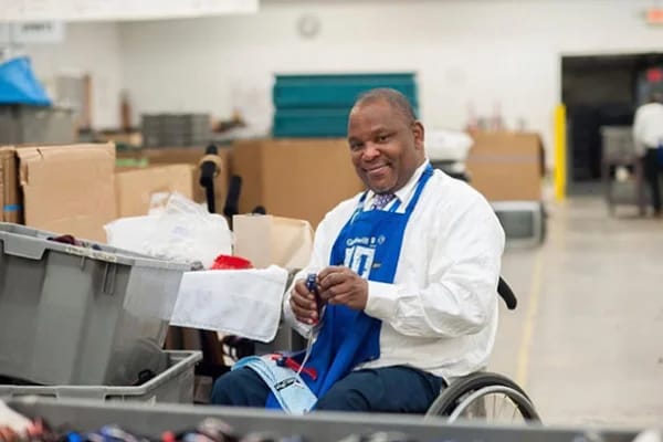 A staff member smiling while working in an indoor space.