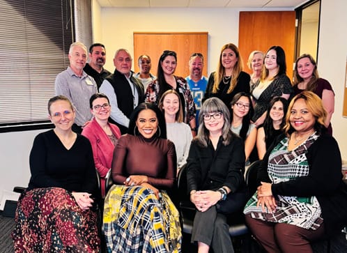 Staff and colleagues posing together in an office setting.