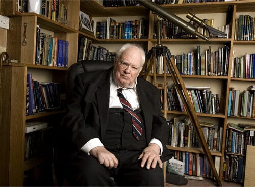 Elderly man sitting in a library with bookshelves
