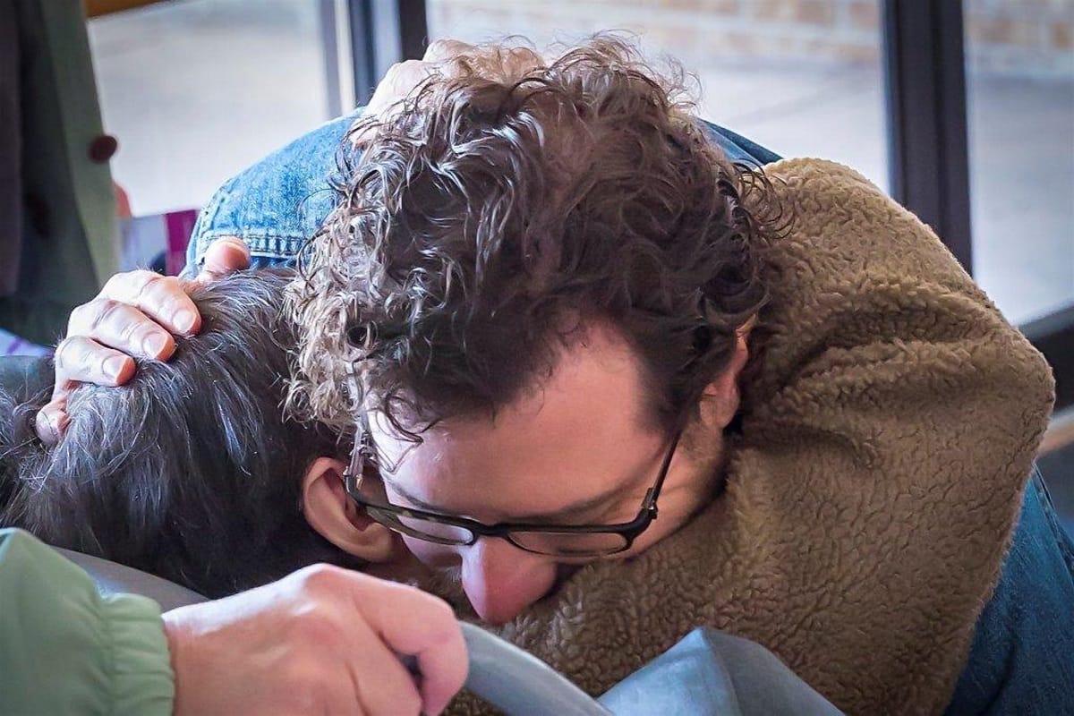 Two individuals embracing in a common area.