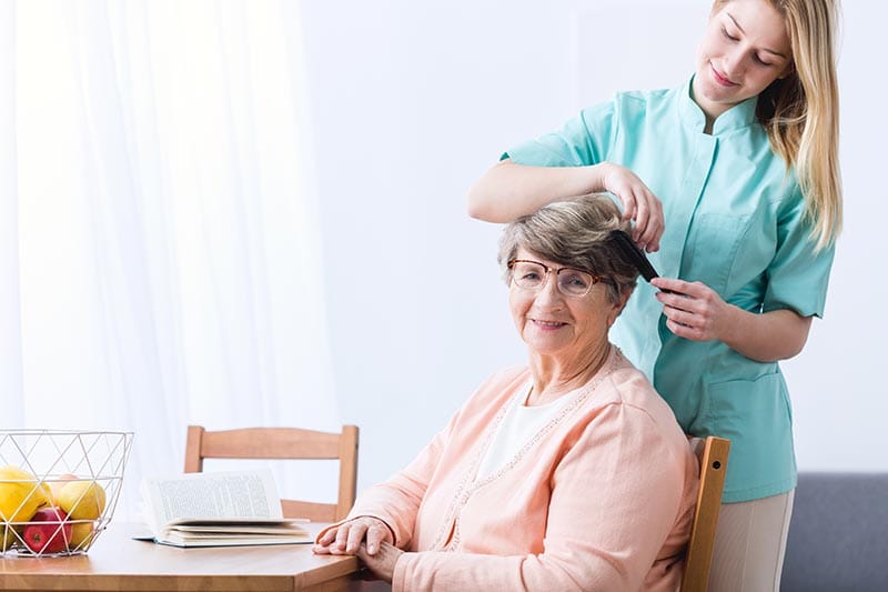 Staff styling resident's hair in a bright interior