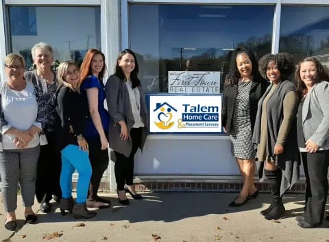 Staff members posing in front of the facility sign.