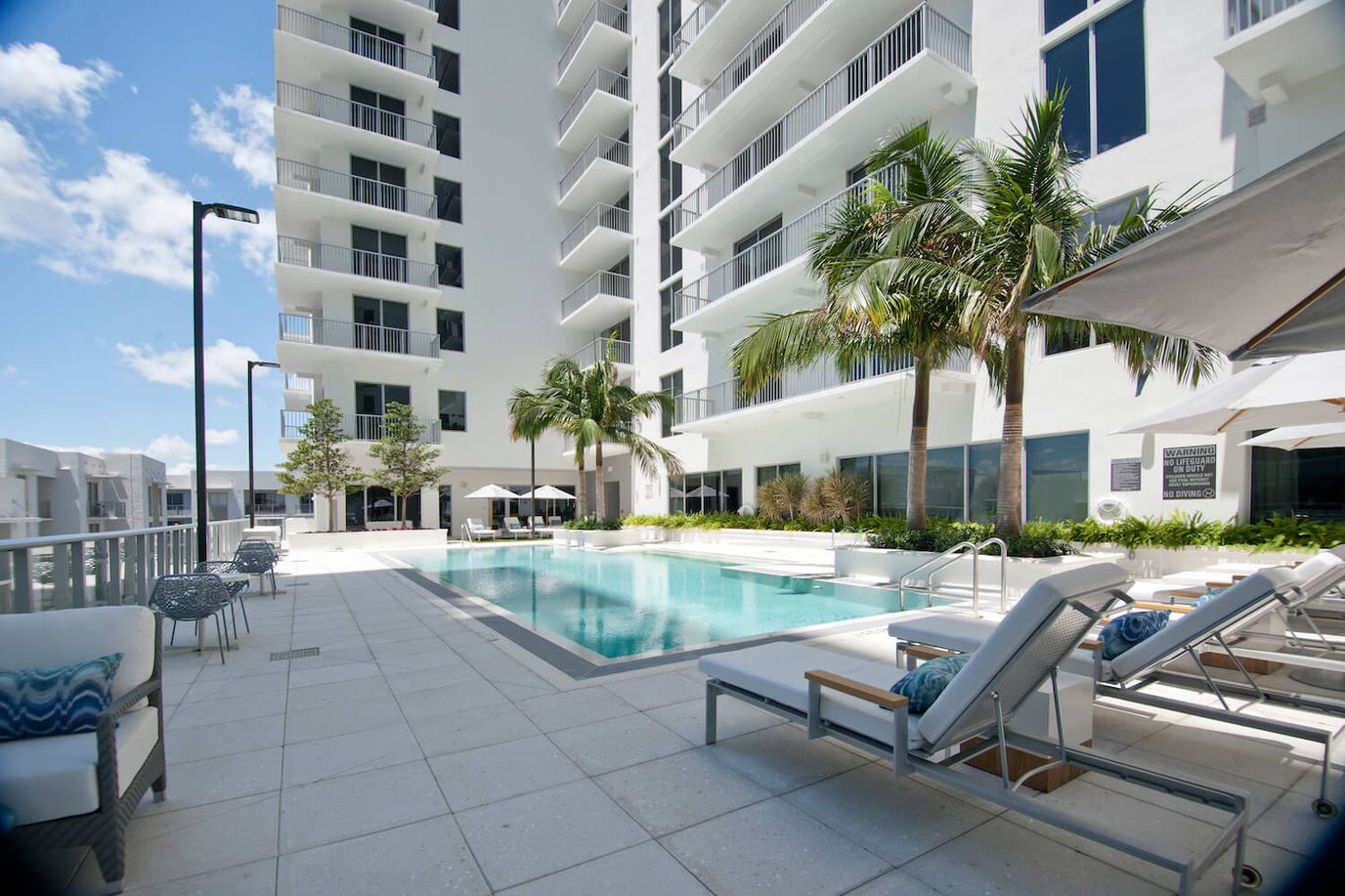 Outdoor pool area with lounge chairs and palm trees