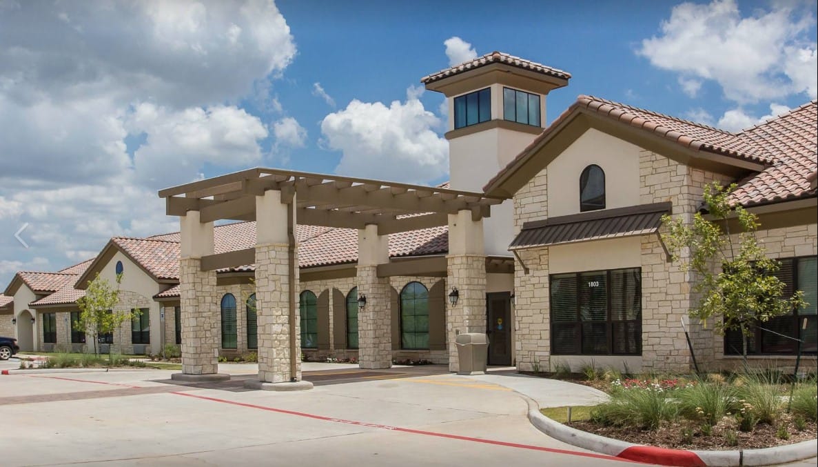 Exterior view of a senior living facility with gardens